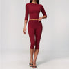 A woman wearing a long-sleeved maroon yoga top and matching leggings set.