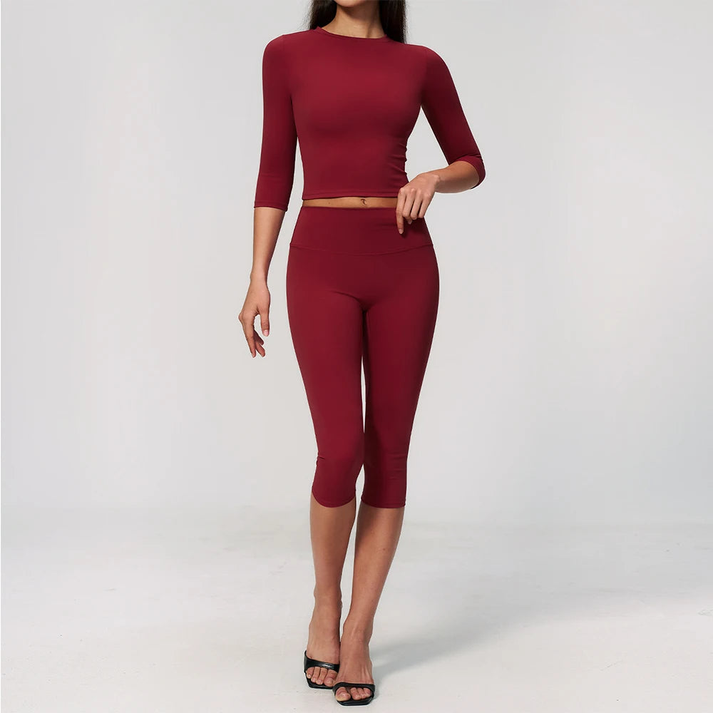 A woman wearing a long-sleeved maroon yoga top and matching leggings set.