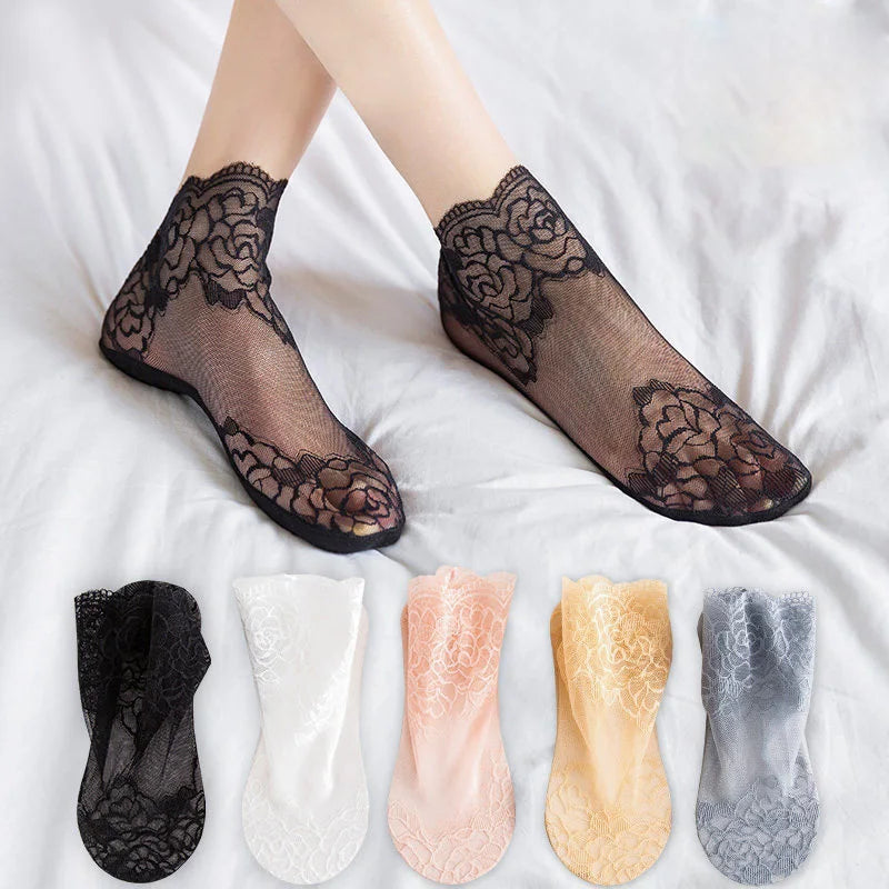 A collection of black, white, pink, yellow, and gray lace mesh ankle socks displayed on a white sheet.