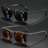 A pair of vintage square sunglasses with dark lenses and brown frames are displayed on a dark surface.