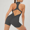A woman wearing a gray backless fitness jumpsuit, shown from the back and side.