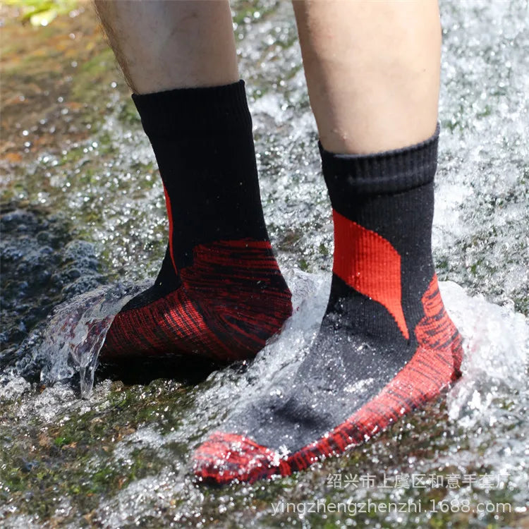 A pair of red and black waterproof breathable hiking socks worn by a person outdoors.