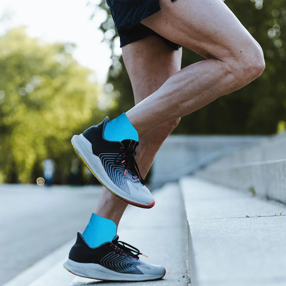 Gros plan d'une personne portant des chaussures de sport noires et bleu vif en train de marcher sur un chemin de béton.