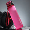 Pinke wiederverwendbare Sportflasche mit rotem Tragegurt vor grauem Hintergrund.