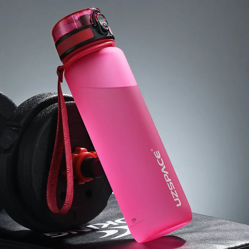Pinke wiederverwendbare Sportflasche mit rotem Tragegurt vor grauem Hintergrund.