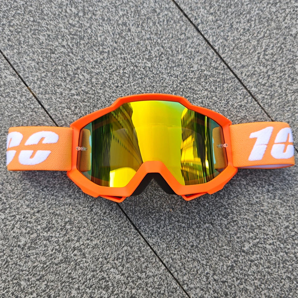 Lunettes tout-terrain orange avec des verres teintés jaunes posées sur une surface grise.