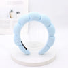 Light blue sponge terry cloth headband for hair styling displayed on a white circular stand.