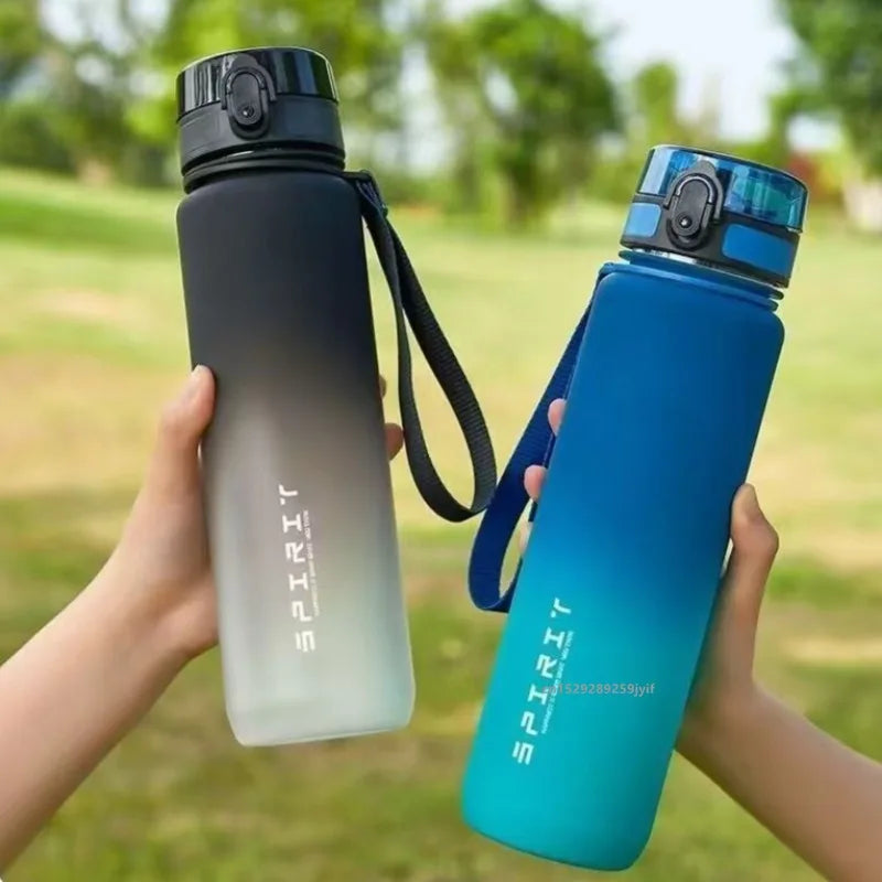 A hand holds a gradient blue sports water bottle with a black cap outdoors.