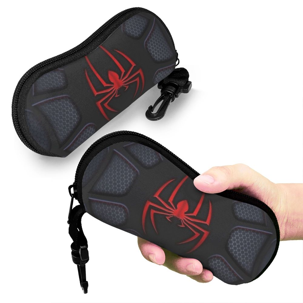 A black silicone pouch with a red spider design is being held by a hand.