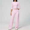 A woman wearing a light pink long-sleeved top and matching high-waisted leggings set for yoga or fitness.