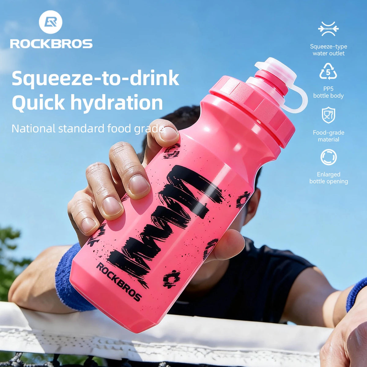 Una mano sostiene una botella de agua Rockbros rosa para beber contra un cielo azul.