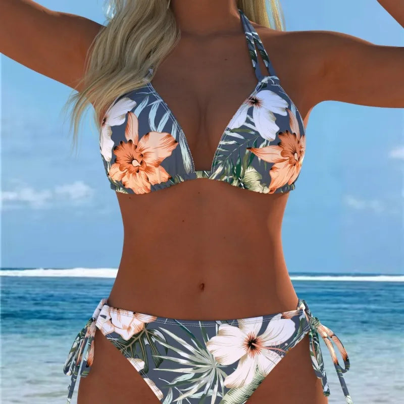 A woman wearing a floral print two-piece bikini swimsuit outdoors near the ocean.