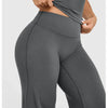 A close-up of a model wearing high waisted wide leg yoga pants in a dark gray color.