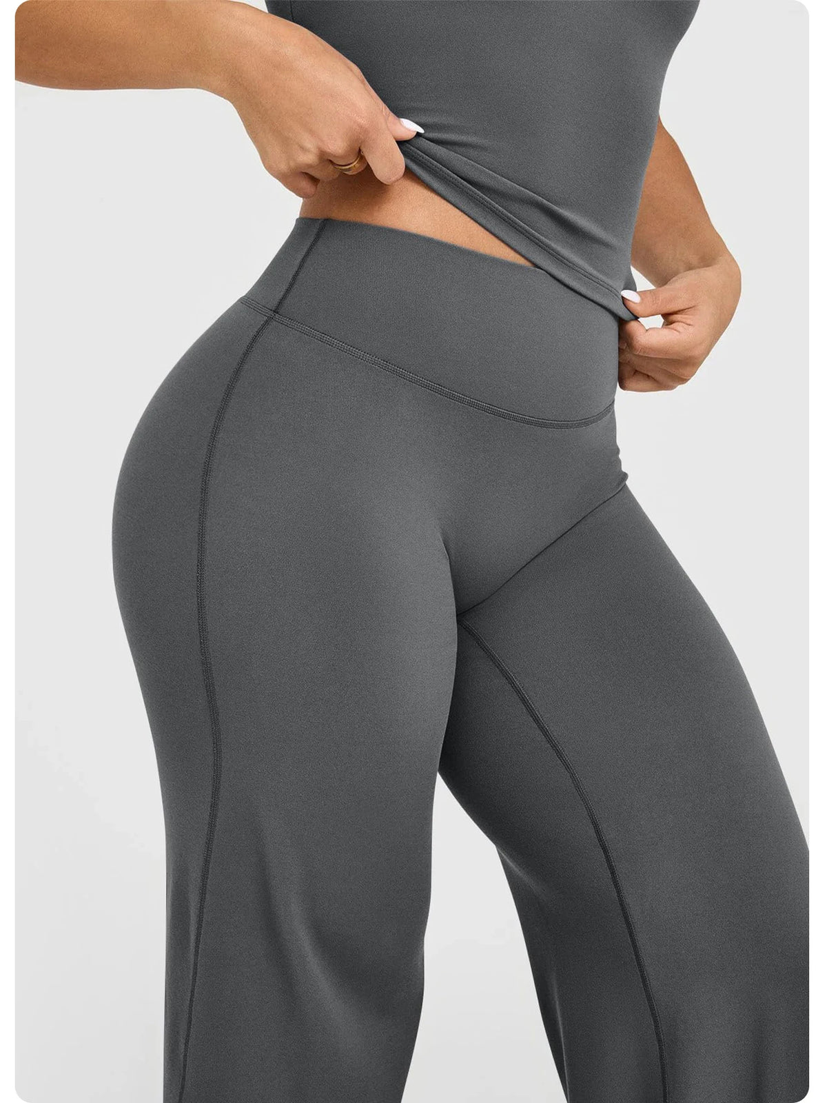 A close-up of a model wearing high waisted wide leg yoga pants in a dark gray color.