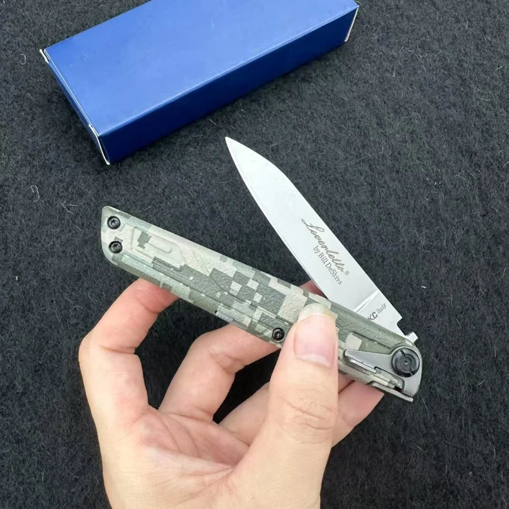 A hand holds a silver folding pocket knife with a camouflage pattern against a dark gray background and a blue box.