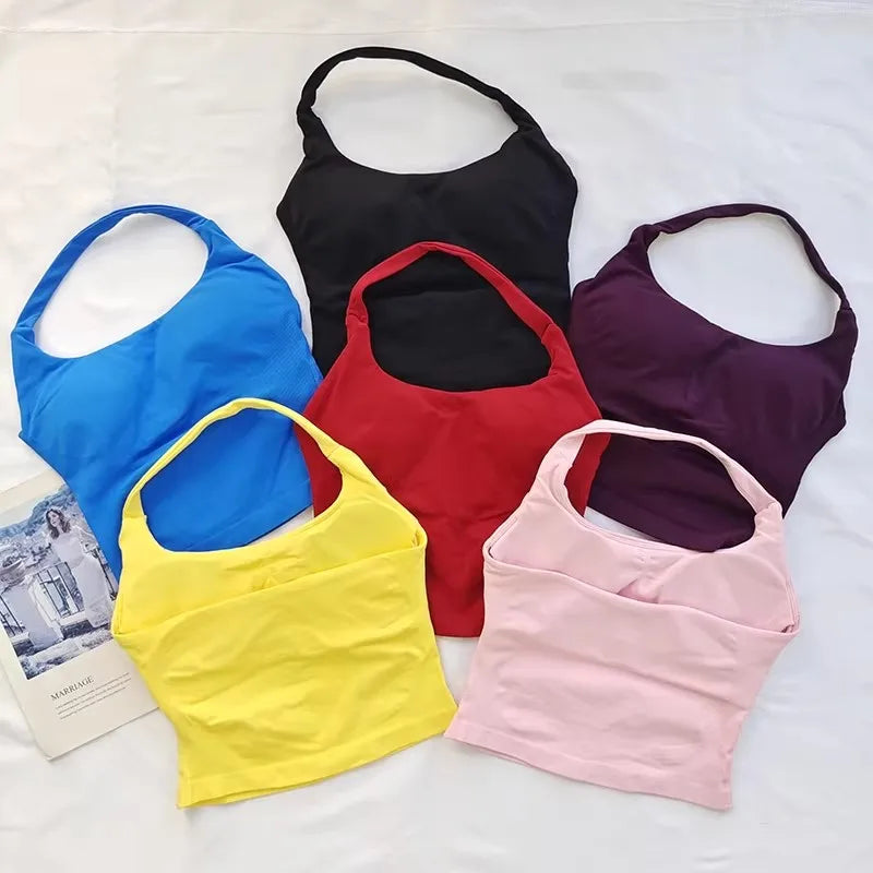 A set of five seamless sports camisoles in black, blue, red, yellow, and purple laid out on a white surface.