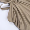 A beige maxi dress with a draped cut-out back, shown in a soft fabric.
