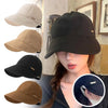 Una mujer modela una gorra de béisbol con ala ancha y protección UV negra en un estudio.
