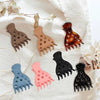 A set of black and nude silicone root lifting hairpin curling clamps displayed on a white linen fabric.