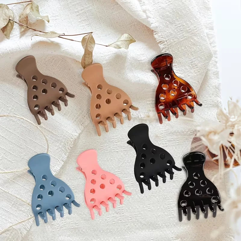 A set of black and nude silicone root lifting hairpin curling clamps displayed on a white linen fabric.
