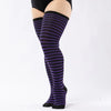 A pair of purple and black striped thigh high leg warmers worn on a person's leg.