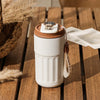 A white thermo mug with a brown lid and temperature display sits on a wooden surface.