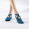 A pair of teal silicone yoga and pilates socks worn on a person's feet.