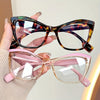 A hand holds a pair of vintage color block blue light blocking eyewear with tortoiseshell and pink frames.