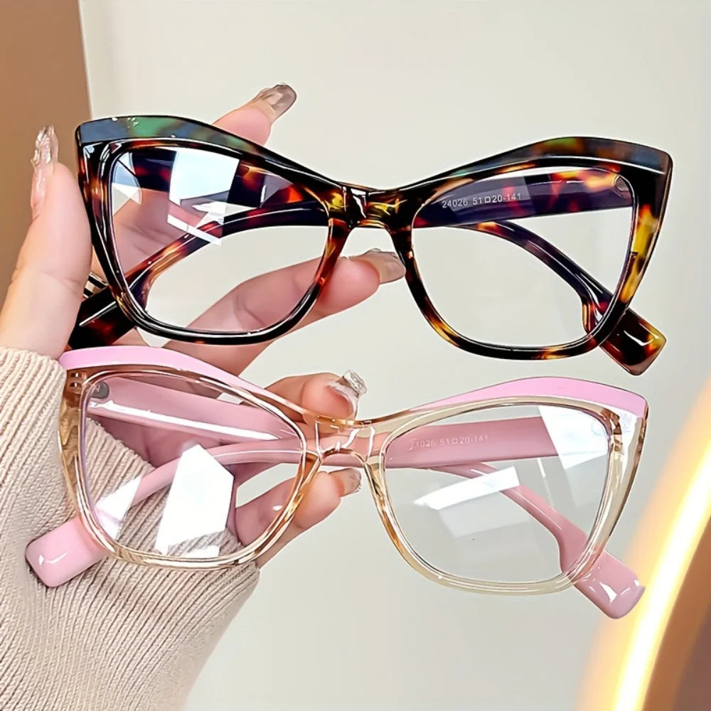 A hand holds a pair of vintage color block blue light blocking eyewear with tortoiseshell and pink frames.