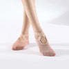 A pair of nude pink breathable silicone yoga and pilates socks worn on a person's feet.