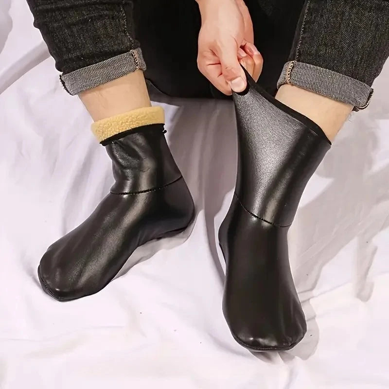 A pair of black leather boots with tan sherpa lining are shown being worn on a person's foot.