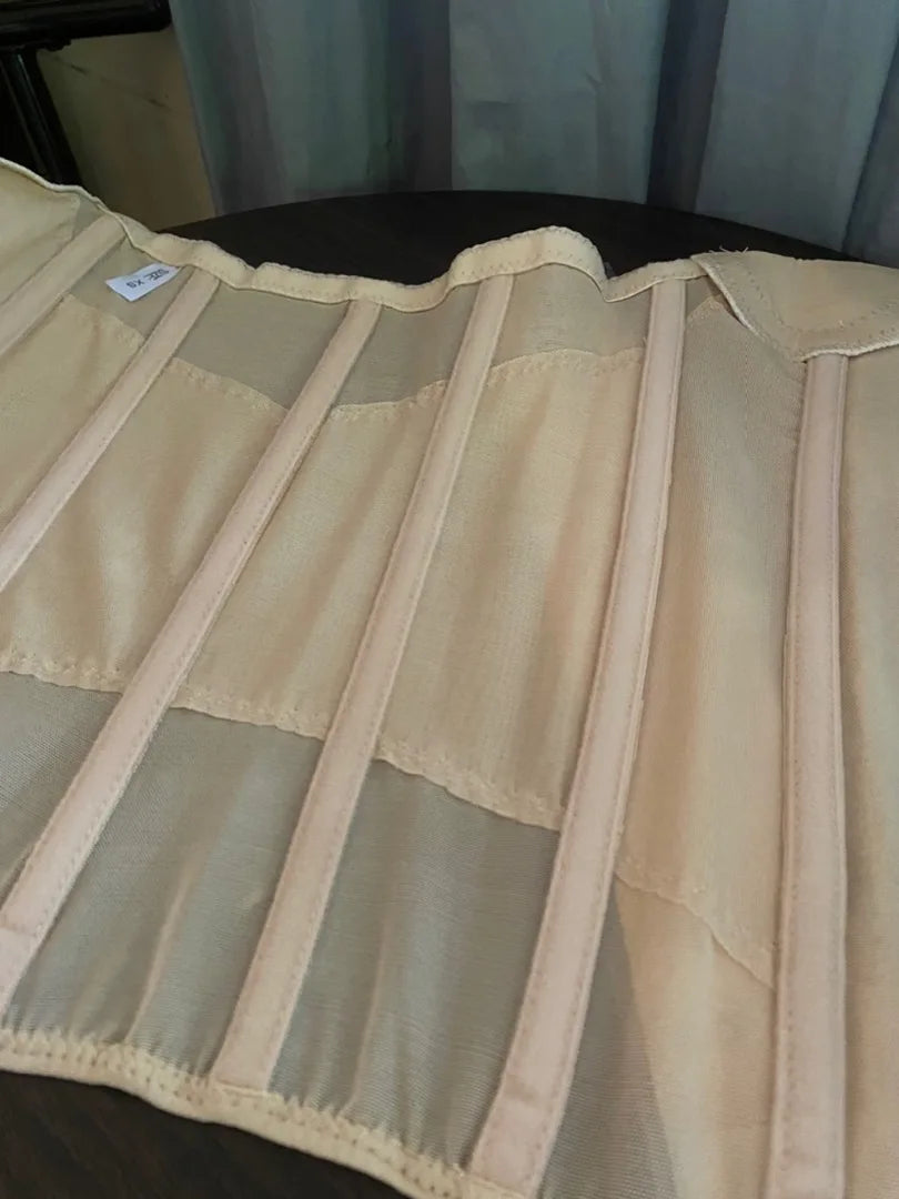 A light beige body shaper waist trainer corset made of sheer fabric with vertical pleats.
