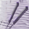 Two purple adjustable ropeless battle ropes lying on a textured surface.