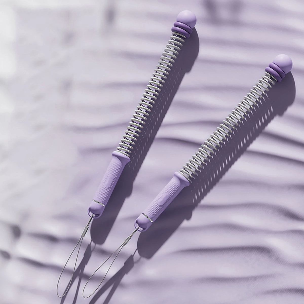 Two purple adjustable ropeless battle ropes lying on a textured surface.