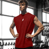 A muscular man wearing a red sleeveless fitness tank top stands in a gym setting.