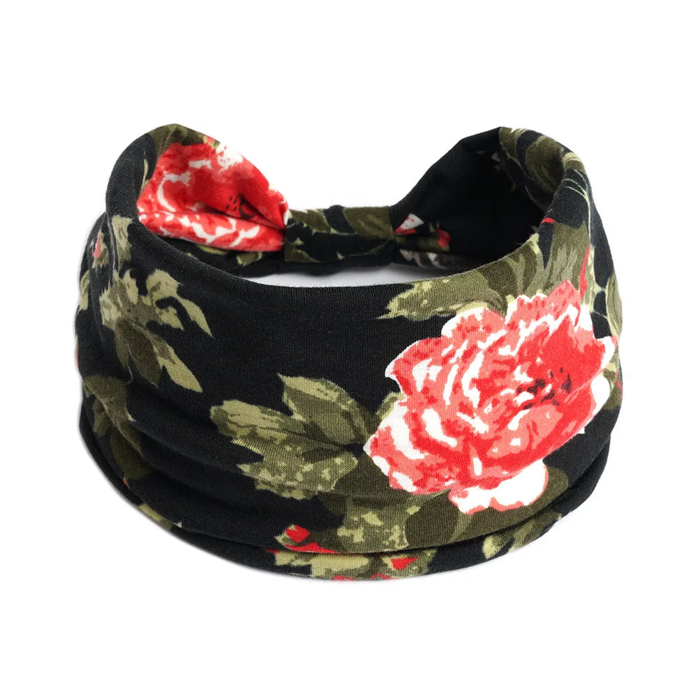 A black fabric headband with a floral print featuring red and green roses.