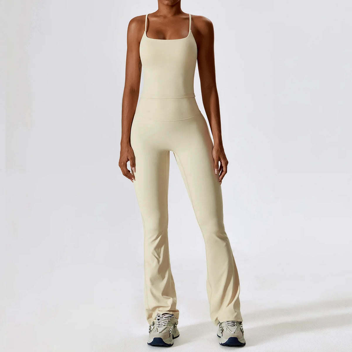 A woman wearing a beige women's performance tracksuit set, including a tank top and matching pants.