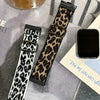A close-up of a black and tan leopard print silicone watch band for a smartwatch, displayed on a surface.