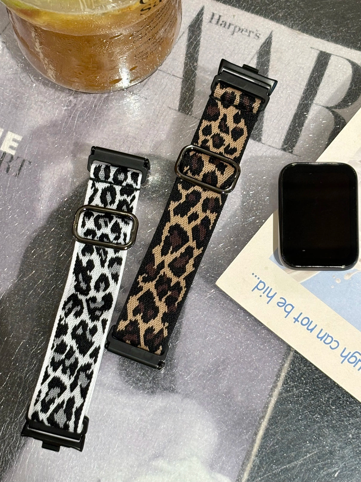 A close-up of a black and tan leopard print silicone watch band for a smartwatch, displayed on a surface.