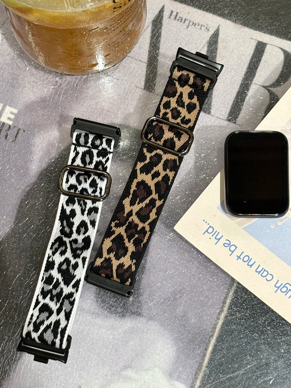 A close-up of a black and tan leopard print silicone watch band for a smartwatch, displayed on a surface.