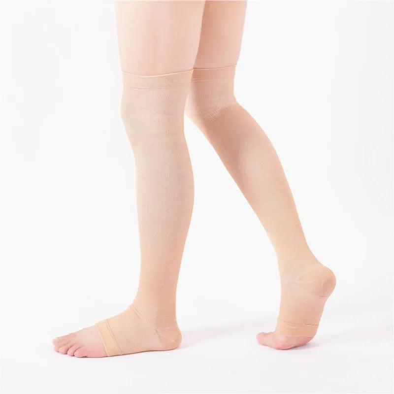 A pair of beige compression thigh high socks worn on a person's legs.
