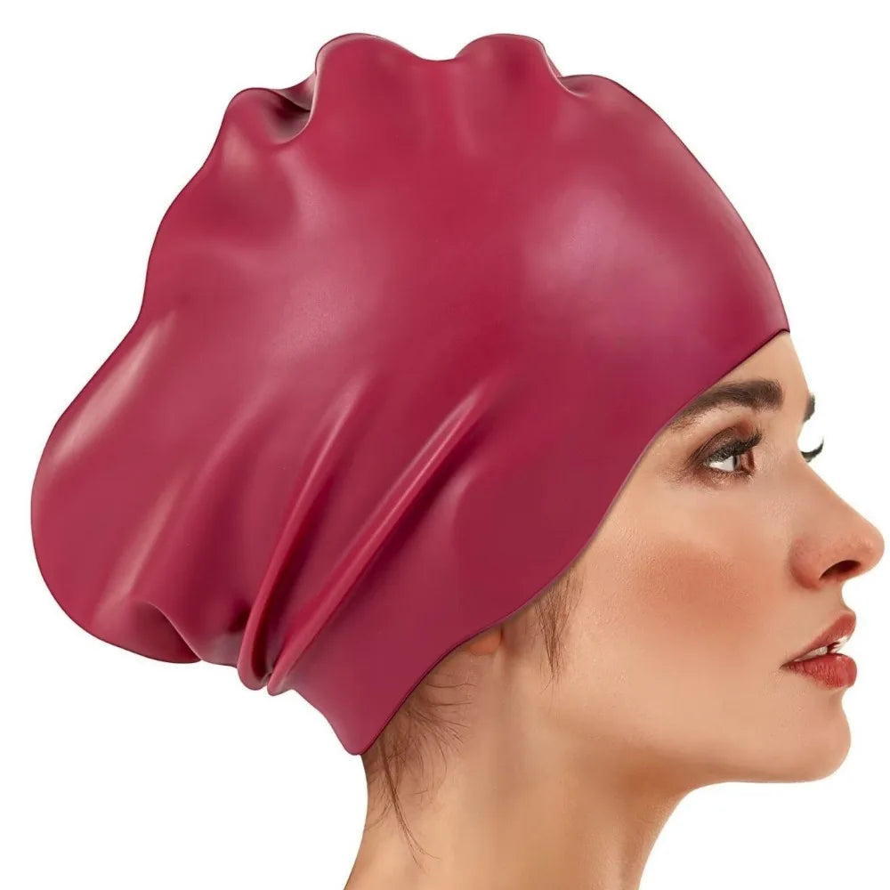 A close-up of a deep magenta silicone swim cap worn on a person's head.