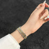 A hand wearing a gold-toned stainless steel watch band for a Huawei fitness tracker.