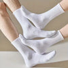 Une paire de chaussettes pour hommes en coton mélangé blanches portées sur les pieds d'une personne.