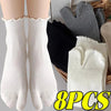 Eight pairs of white knit crew socks with ruffle cuffs displayed next to gray and black knitted gloves.