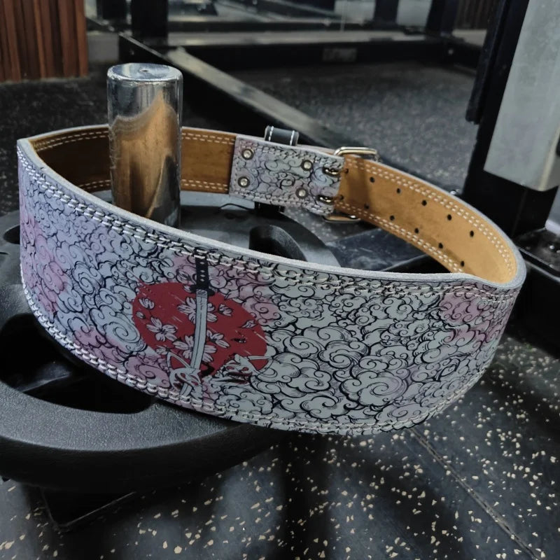 A patterned leather weightlifting belt with a silver metal rod and buckle resting on a black gym mat.