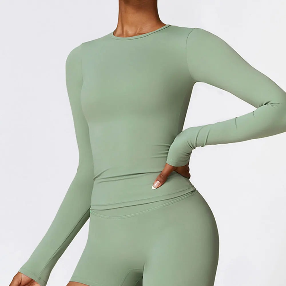 A woman wearing a long sleeve olive green yoga and fitness t-shirt.