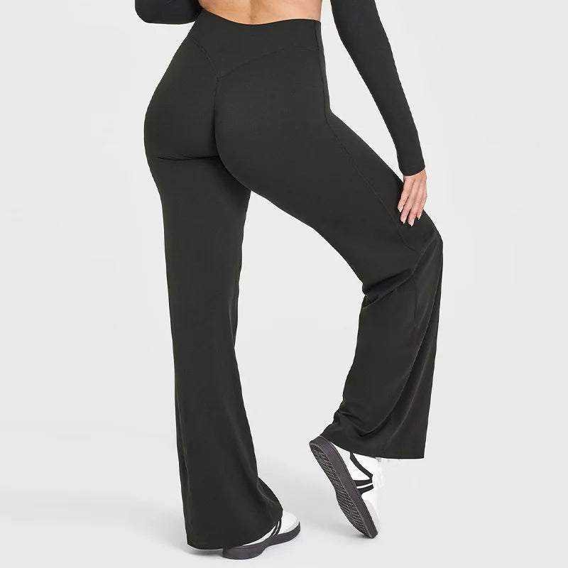 A model wearing black high-waist yoga pants and a black top, shown from the side.