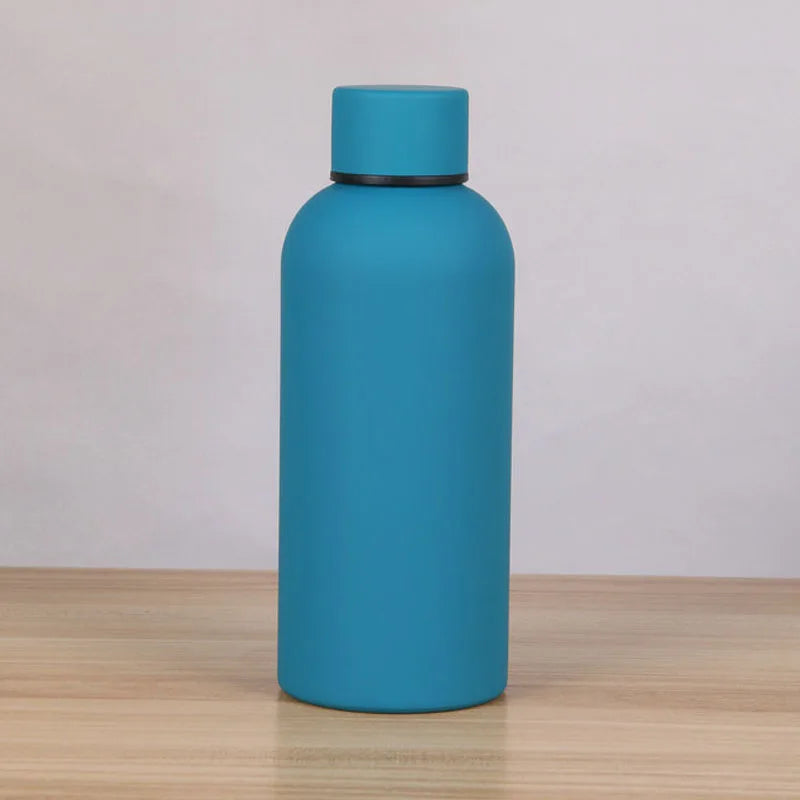A sleek, matte blue double-layer vacuum thermos cup standing upright on a wooden surface.