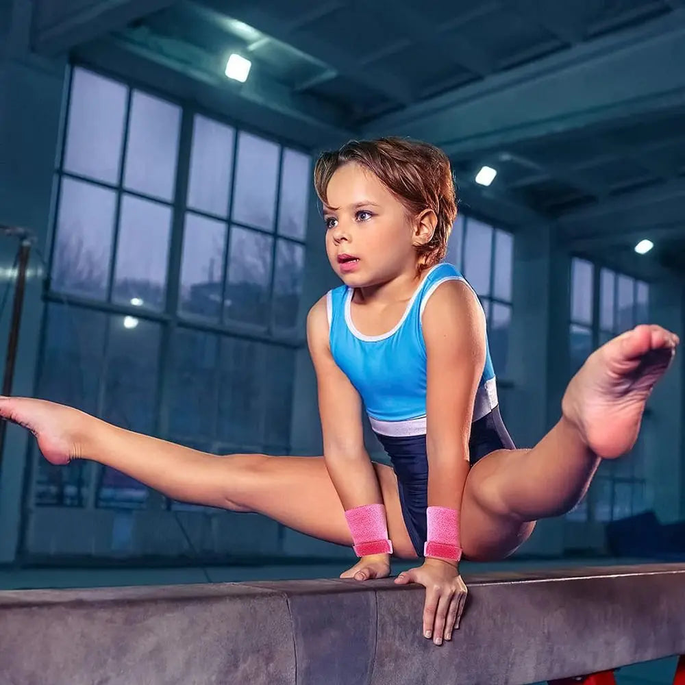 A young girl performing a gymnastics move while wearing wristbands on a padded surface.